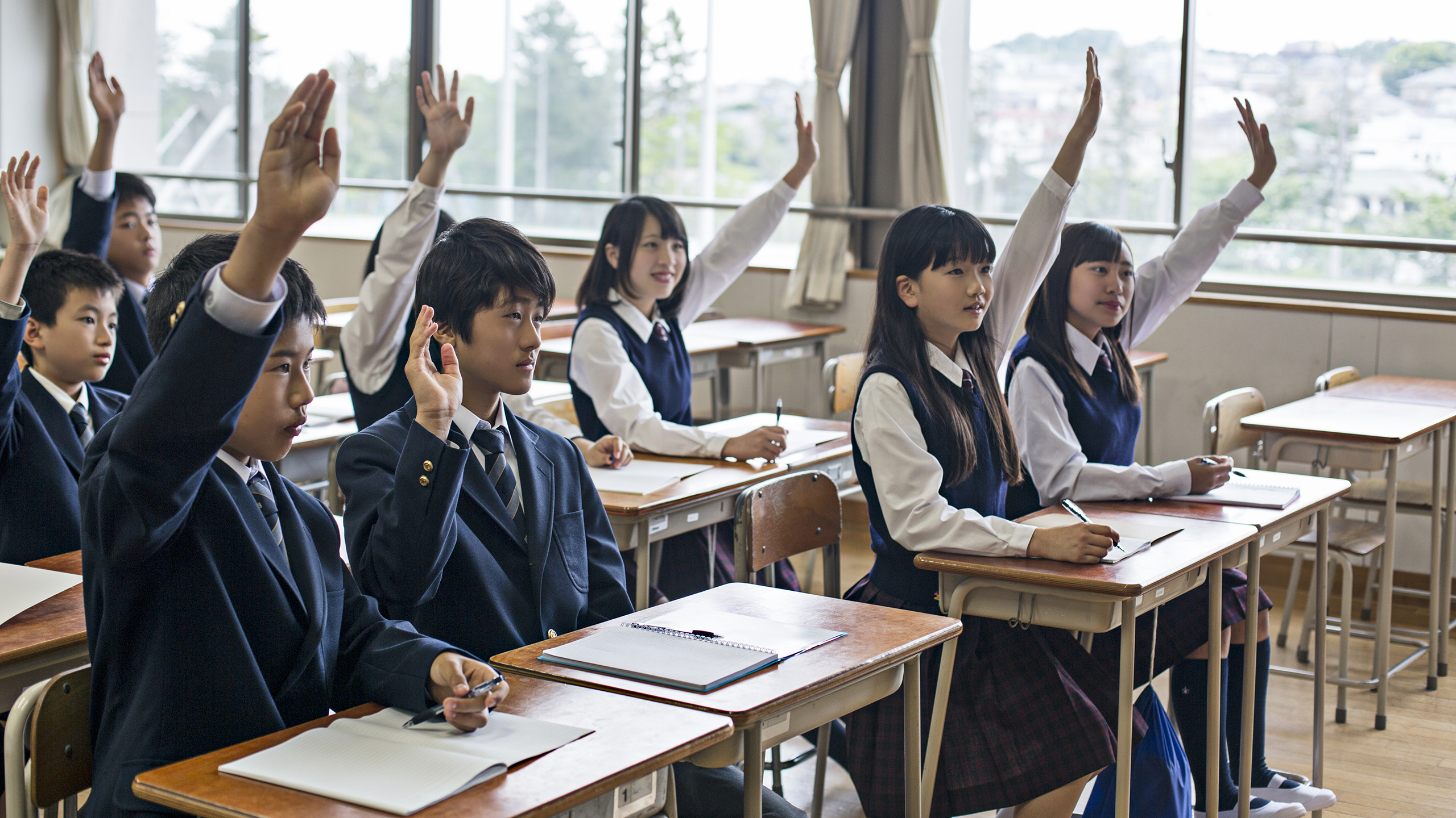 Image of students raising hands in classroom