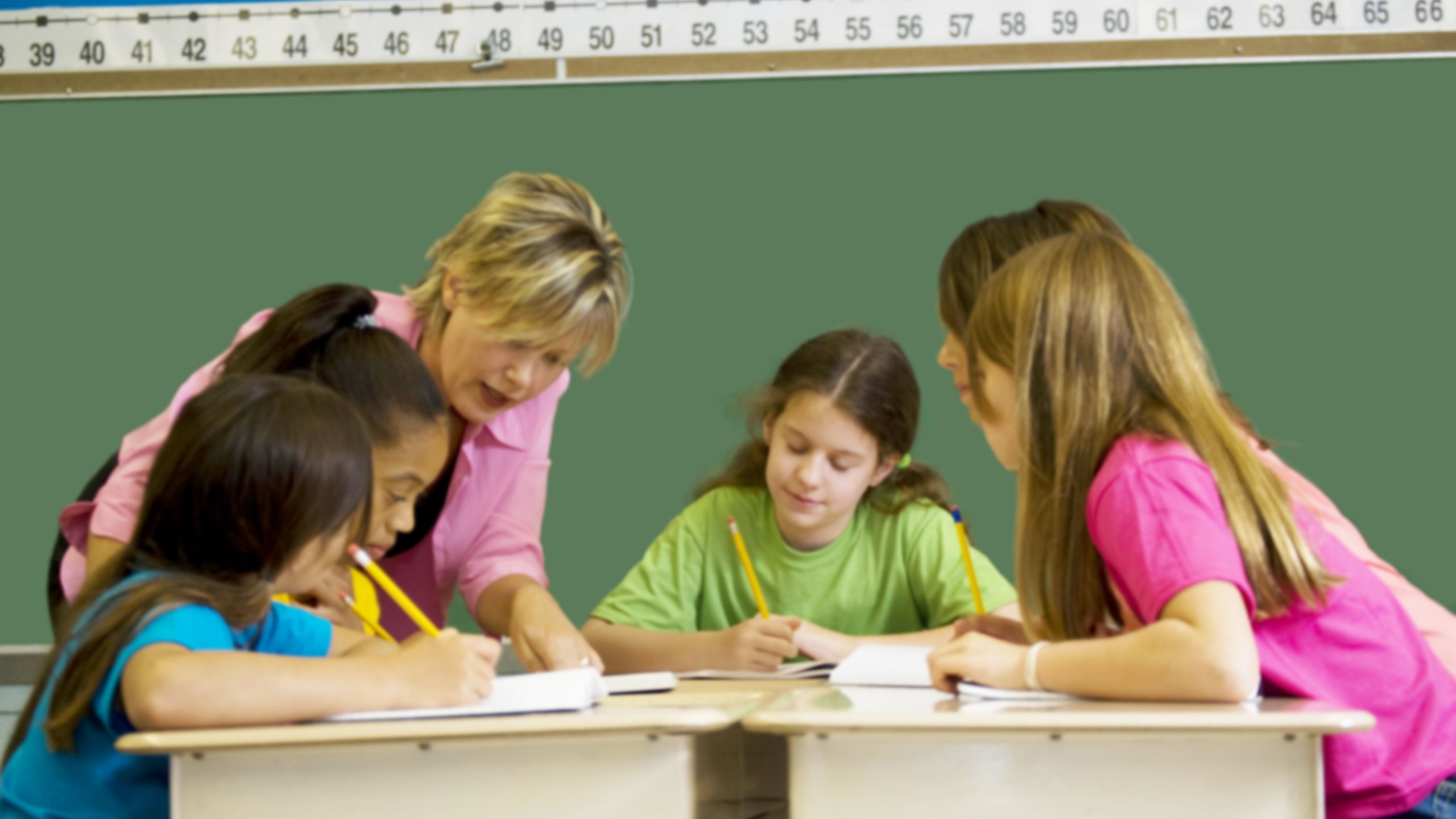 Image of a teacher helping a table of young students.