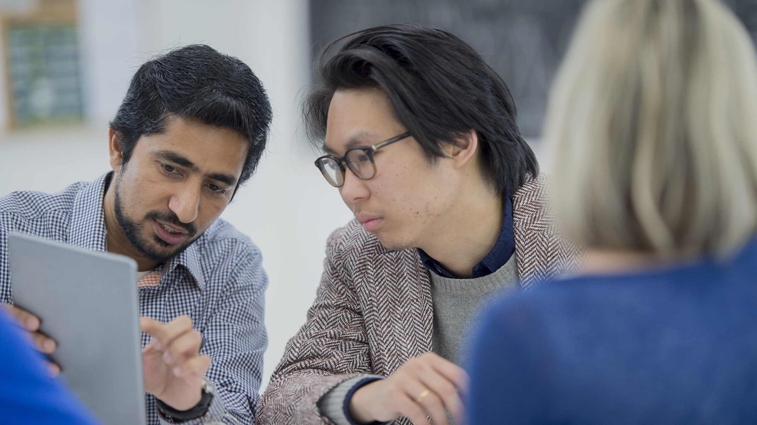 Two men looking at something on a laptop and talking.