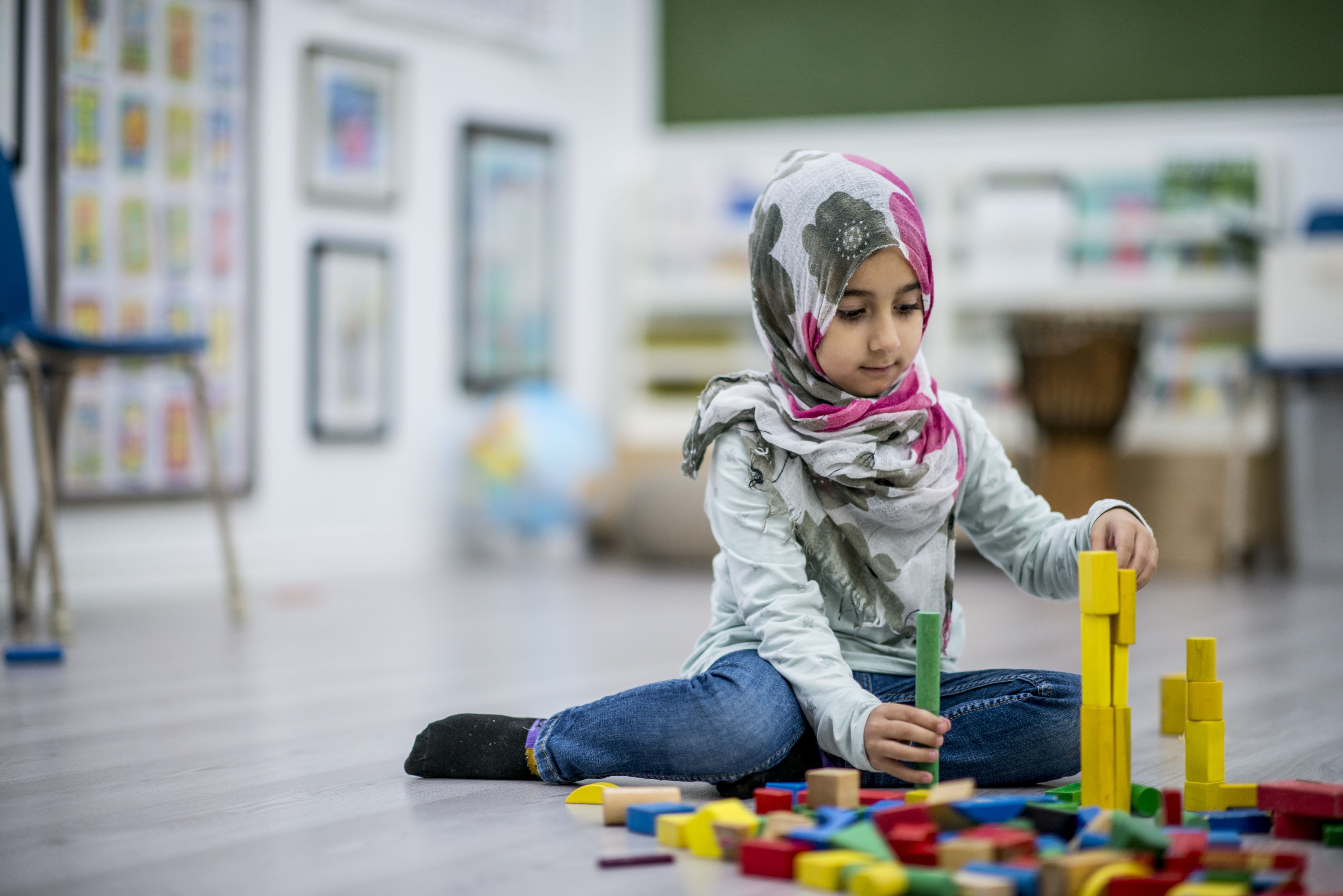 Girl wearing hijab playing with coloured blocks