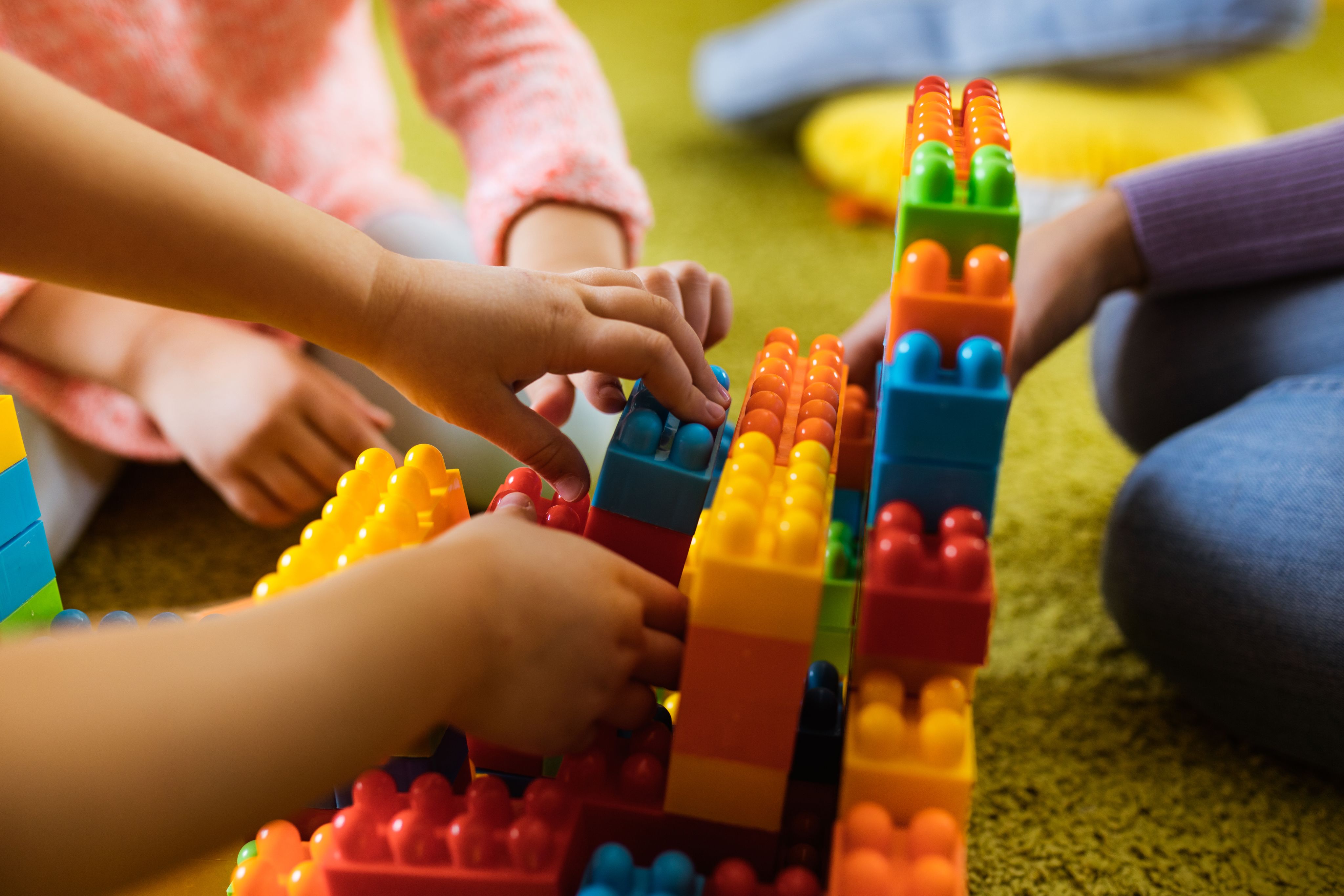 Child's hand playing with colourful interlocking bricks