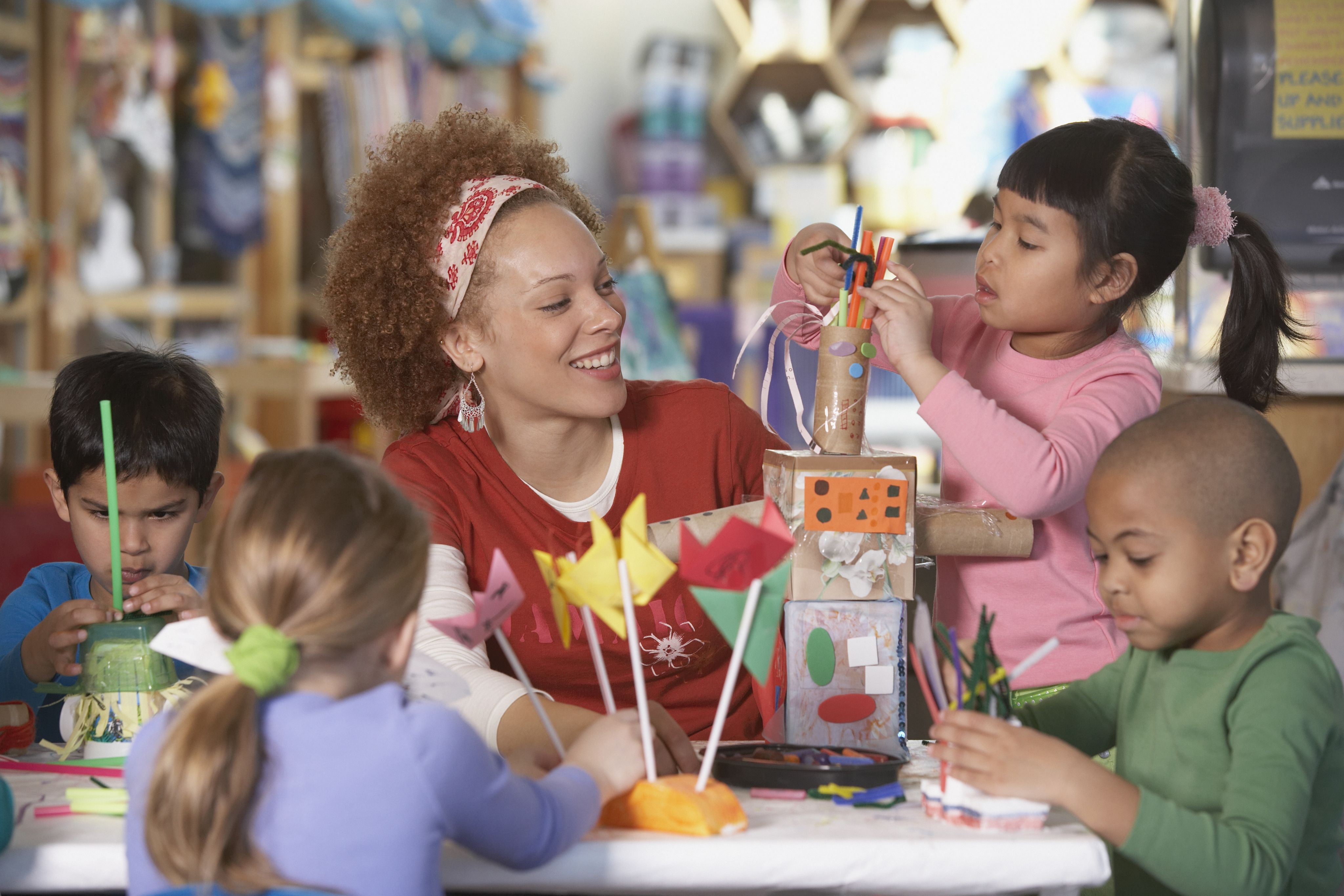 Teacher with group of children constructing objects from craft resources
